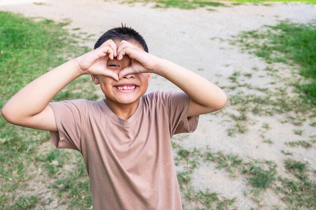 The boy smiled happily happy, heart shape with hands