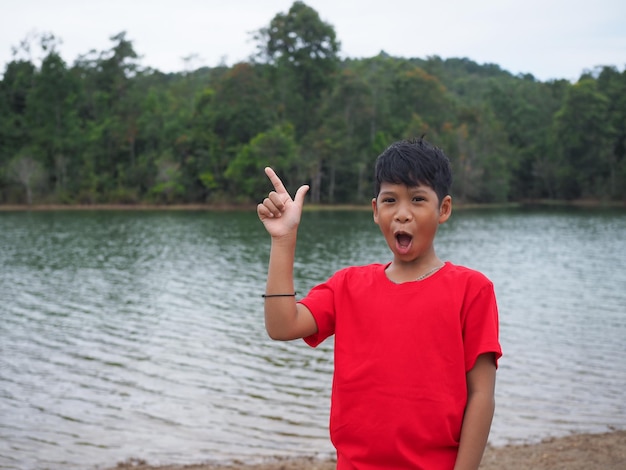 The boy smiled and pointed his hand to his side On the background is a reservoir