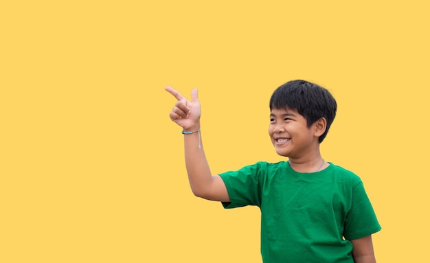 The boy smiled and pointed his hand to his side on a yellow background