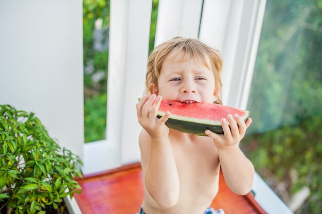 Boy smiling and eating watermelon