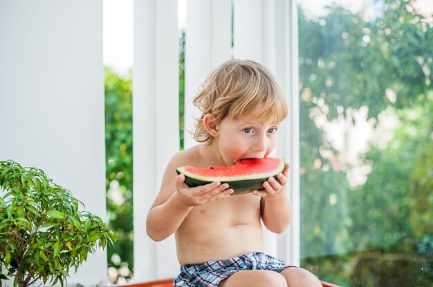 笑顔でスイカを食べる少年