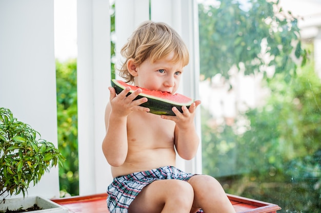 笑顔でスイカを食べる少年