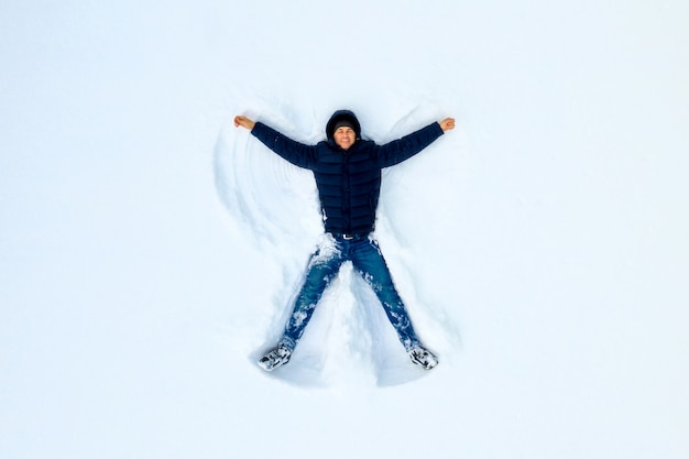 The boy on a snow flapping arms and legs angel shows.