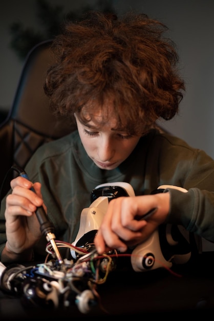 The boy spends time at home at desk digging into the electronics that power the robot