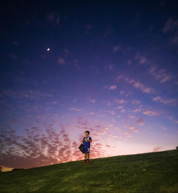 Photo boy in sports clothing on hill at sunset