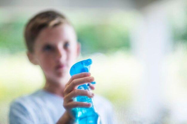 Foto ragazzo che spruzza con il detergente per finestre