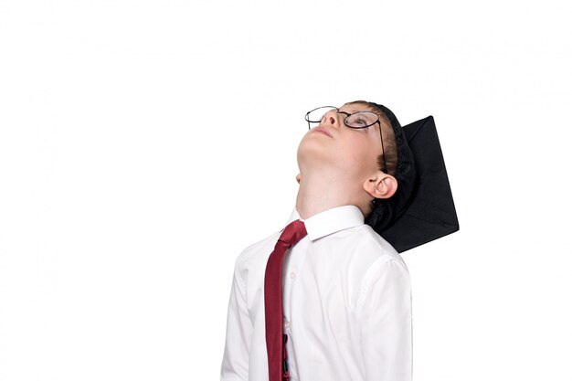 Boy in a square academic hat and glasses lookong up