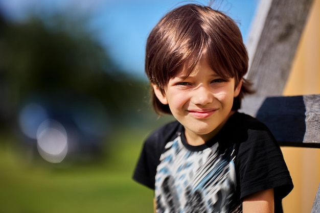 Boy squints from sun while posing for photographer on bright sunny day