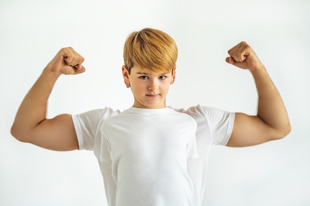 白い背景の上の筋肉の男の前に立っている少年