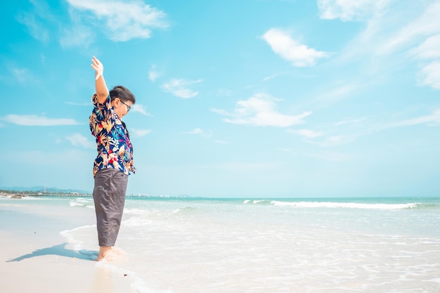 Photo boy standing on the beach during the summer time enjoying the view