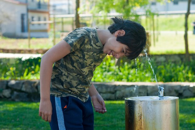 Foto ragazzo in piedi vicino alla fontana nel parco