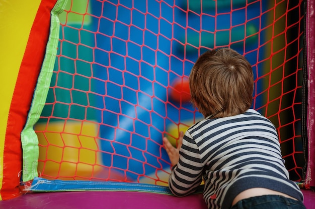 Boy standing by net at indoors playground