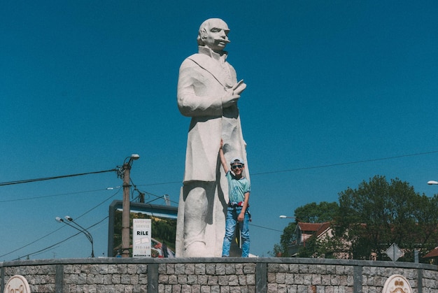 Foto ragazzo in piedi accanto alla statua contro un cielo limpido