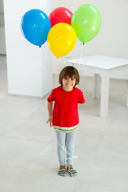 Boy standing and holding a bunch of balloons in his hand