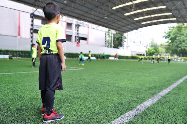 Мальчик, стоя на юношеской тренировке по футболу.