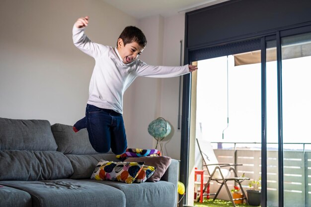 Boy standing on sofa at home