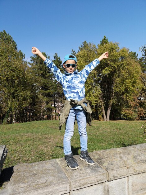 Boy standing on wall against trees