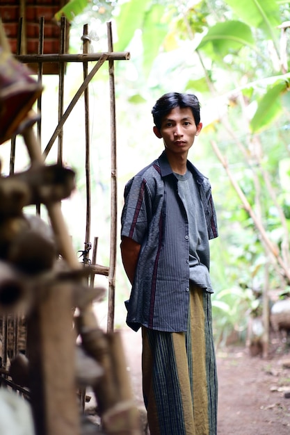 A boy stands in front of a house in a village in the northern province of thailand.