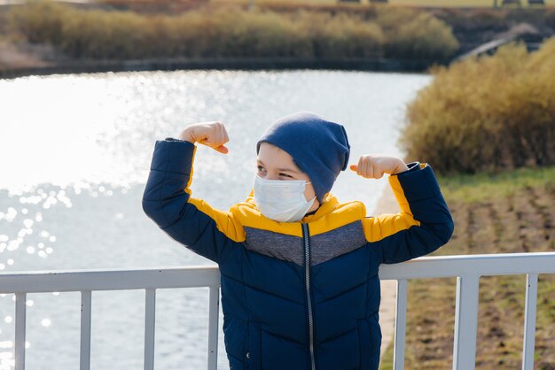 A boy stands on a gray space in a mask during a quarantine with free space. Quarantine in the mask.