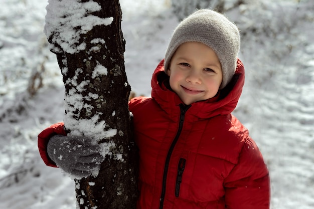 boy stands next to a tree in a winter forest