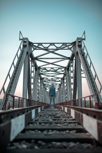 The boy stands with his back on the bridge in the center