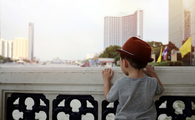 A boy stands with his back on the river.