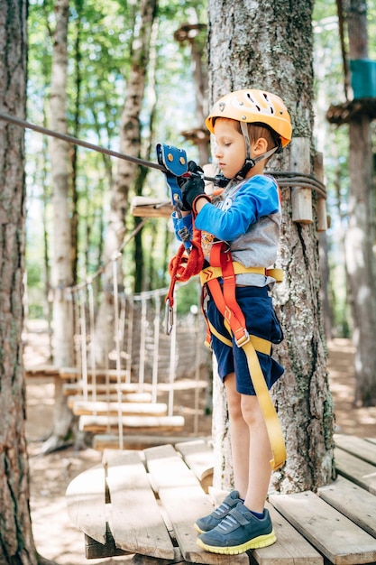 Boy stands on a wooden platform and looks at the safety\
belt