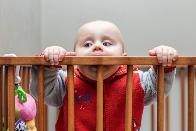 Foto ragazzo che soggiorna in un cortile in legno per bambini e box per bambini graffiare le gengive con traversa in legno per aiutare nella dentizione del bambino