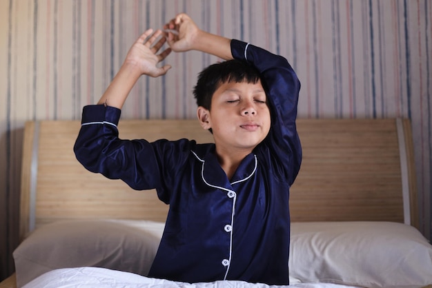 Boy stretching in bed after waking up