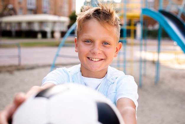 Photo boy stretching soccer ball to the camera