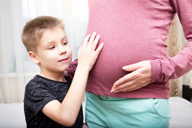 The boy strokes the pregnant belly of his mother Maternity and pregnancy