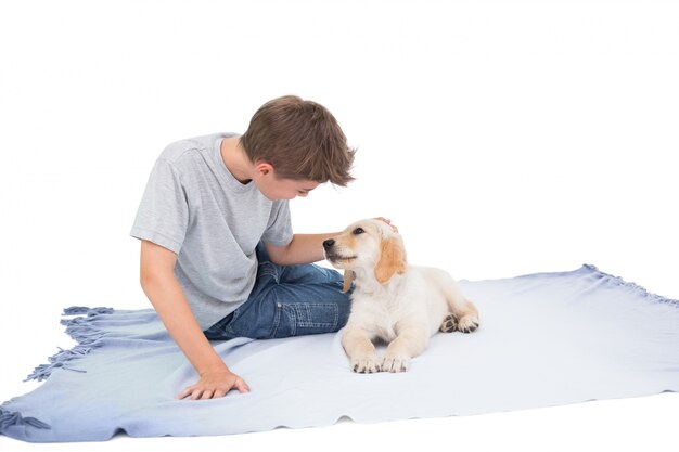 Boy stroking puppy on blanket