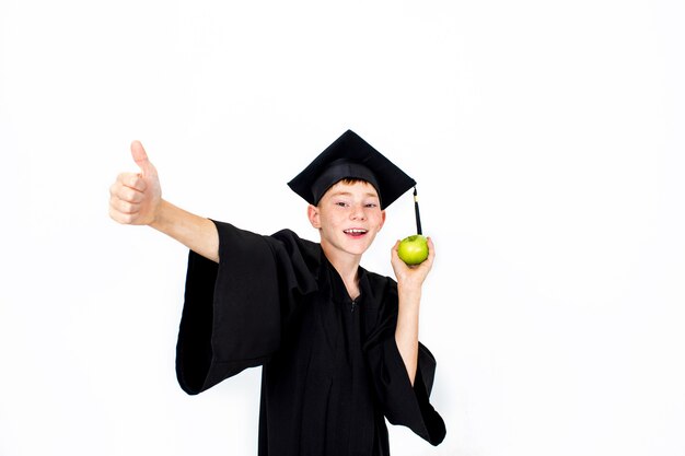 A boy in a student hat with an Apple in his hand. Knowledge, education and successful career.