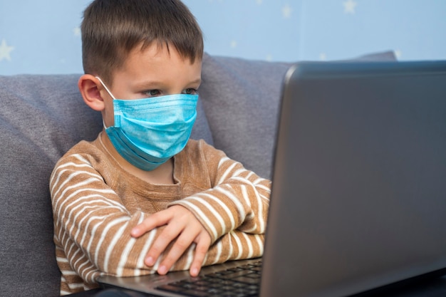 Boy studying at home in a medical mask  Distance learning during quarantine concept