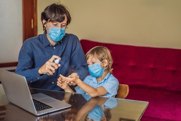노트북을 사용하여 집에서 온라인으로 공부하는 소년 아버지는 그가 코로나 바이러스로부터 보호하기 위해 의료용 마스크와 소독제를 사용하는 아버지와 아들을 배우도록 도와줍니다 검역 기간 동안 공부합니다 글로벌 전염병 covid19 바이러스