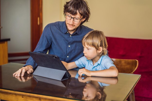 태블릿을 사용하여 집에서 온라인으로 공부하는 소년 아버지는 검역 기간 동안 공부하는 것을 돕습니다 글로벌 유행병 covid19 바이러스