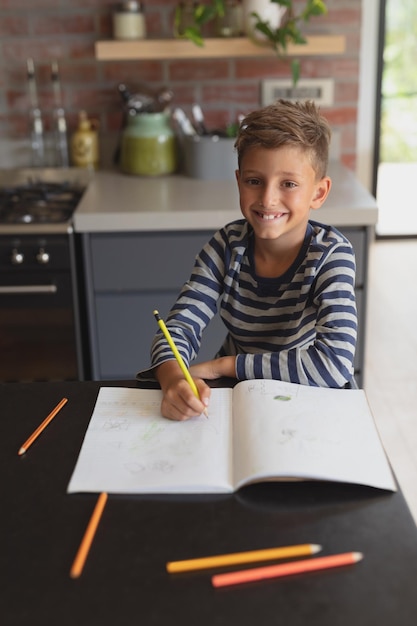 家のキッチンのテーブルで勉強している少年