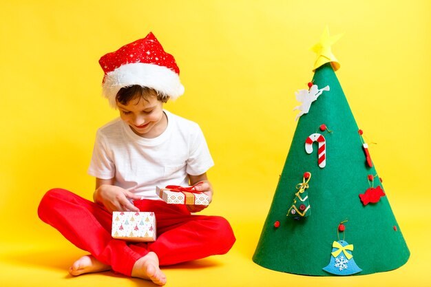 boy in suit of Santas hat on yellow wall. Concept christmas and new year holidays