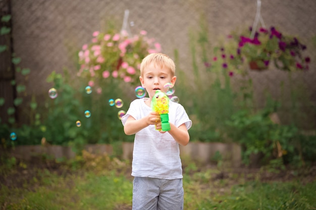 Boy in summer playing with water and soap bubbles close-up and copy space.