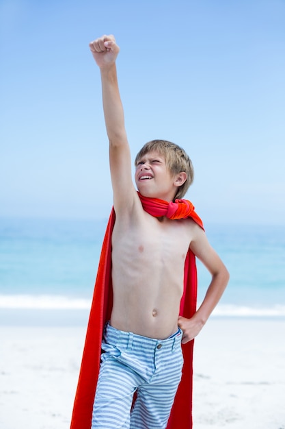Boy in superhero costume with hand raised