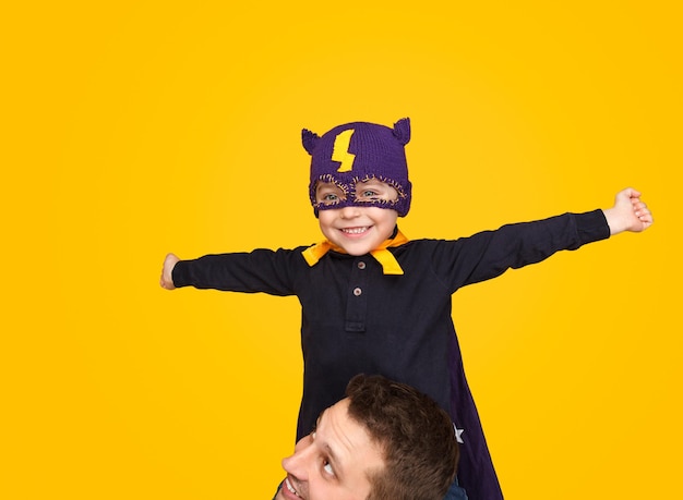 Boy in superhero mask sitting on neck of father