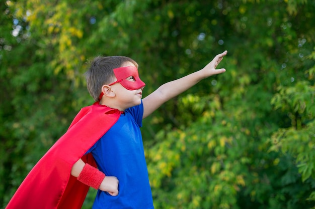 Foto ragazzo in costume di superman in piedi contro un albero