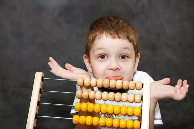 Boy in surprise spread his arms near the wooden abacus.