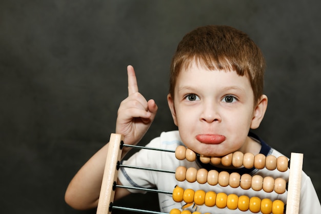 Boy in surprise spread his arms near the wooden abacus.