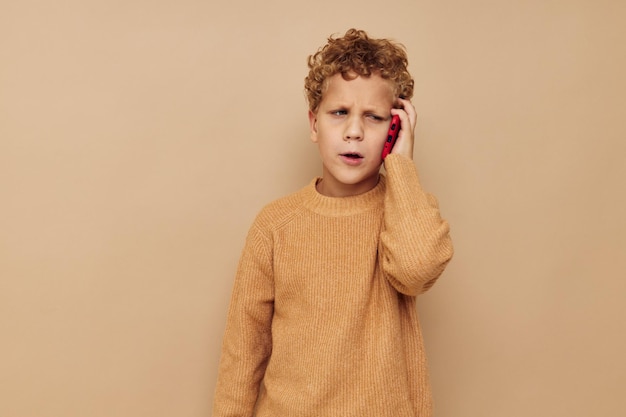 Boy in a sweater with a phone in his hands technology beige background