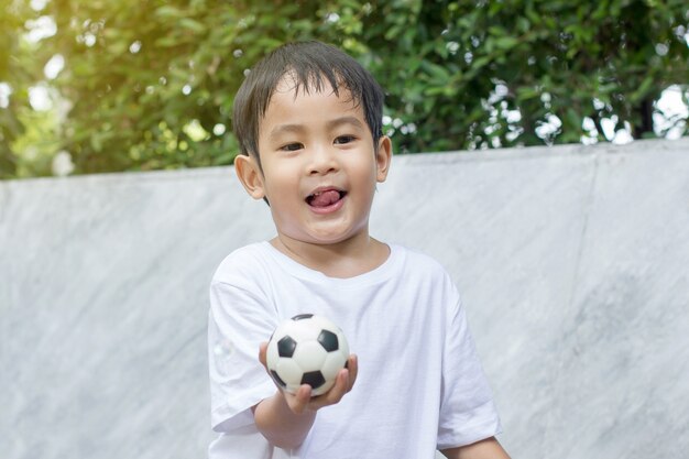 少年は発汗し、小さなサッカーのおもちゃを遊ぶことから疲れた。