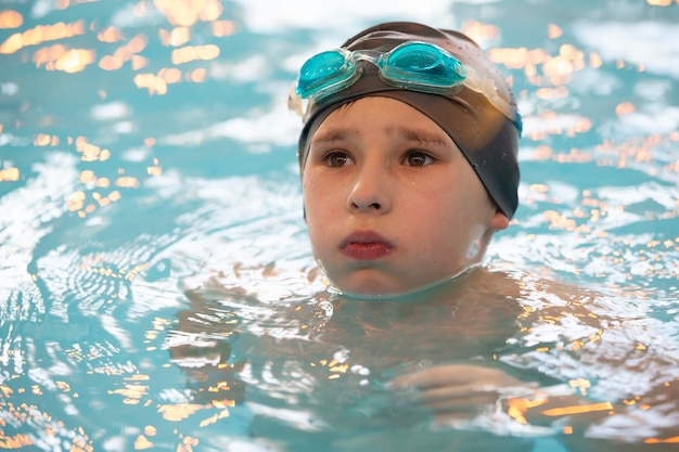Boy in a swimming cap and swimming goggles in the pool The child is engaged in the swimming section
