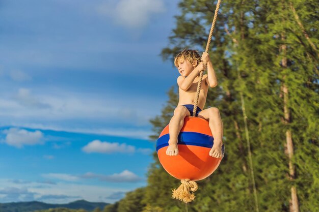 ビーチでブランコに乗っている男の子ママと息子はビーチで時間を過ごします