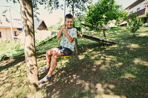 Boy swinging on a rope against slide in mountain village