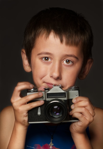 The boy takes a photo on a 35 mm film camera